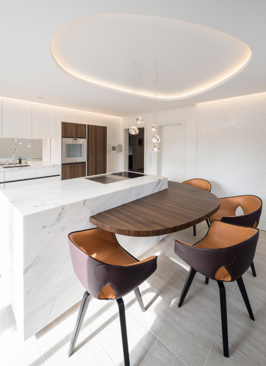 ITALIAN TOUCH project from Reimann for modern interior design ideas, kitchen space with a white marble kitchen, some suspension lights, 4 counter stools in a leather, material and a brownish colour.   italian touch 01  Reimann Architecture Modern Interior Design Ideas